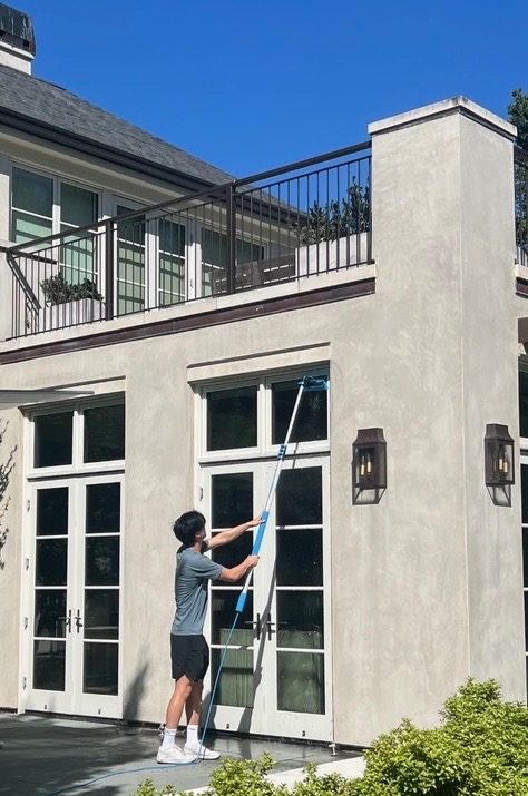 CleanView technician cleaning tall windows with an extension pole